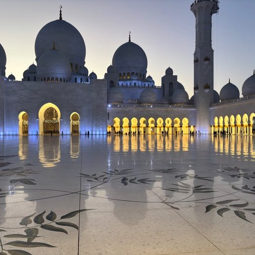 The white marble courtyard of the Sheikh Zayed Grand Mosque in Abu Dhabi at dusk